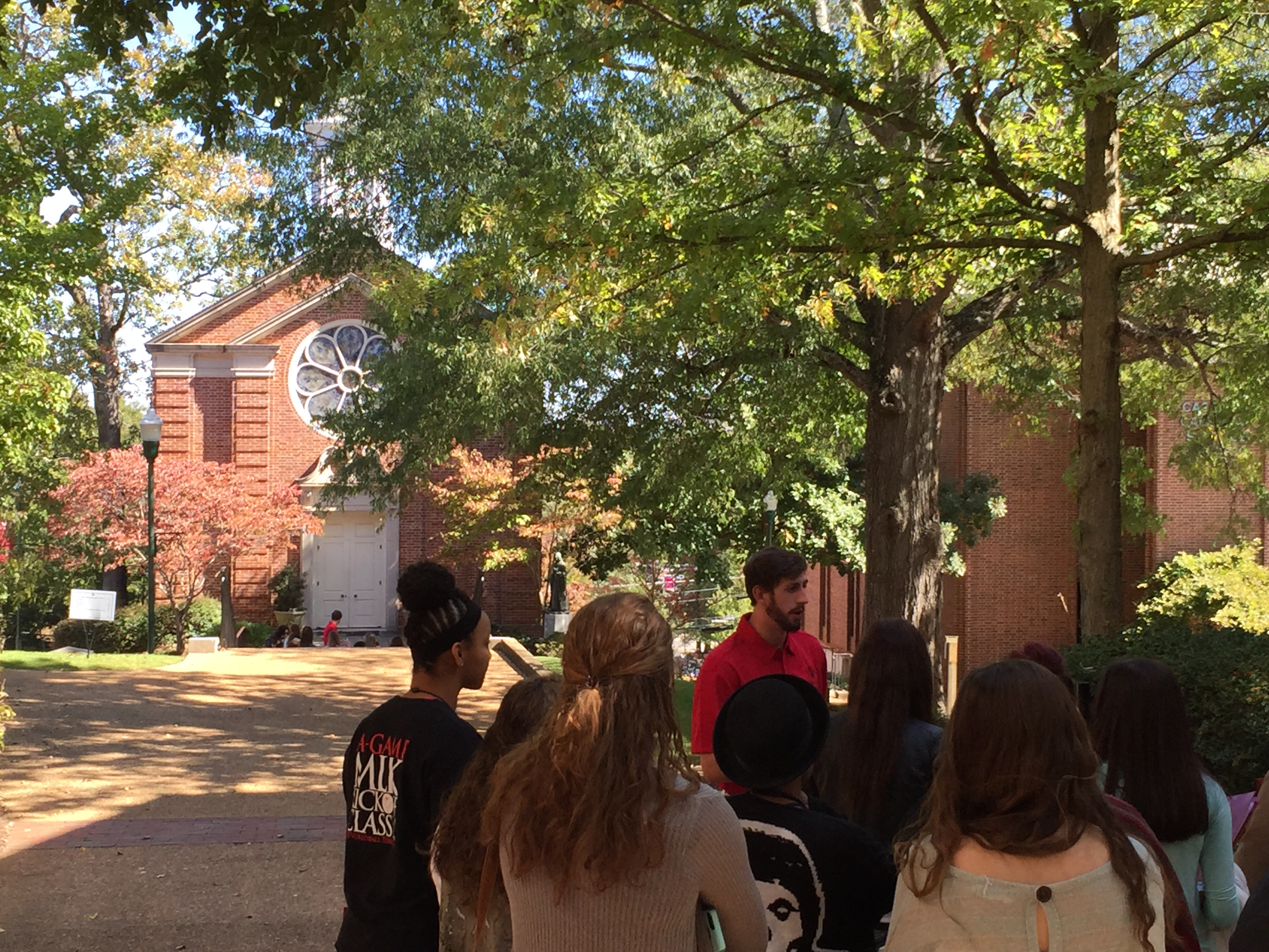 A group of students takes a tour of campus on a beautiful blue sky day