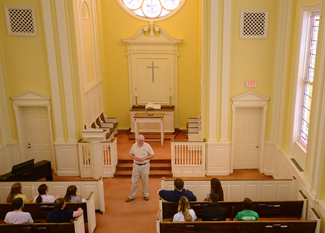Male professor addresses a small group of students int he college chapel